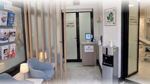 Un centre mèdic amb una zona de recepció, un despatx mèdic i un dispensador d'aigua.