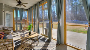 A covered porch with wicker furniture, a ceiling fan, and large windows with curtains. - Spacious 5BR Masters Retreat: Heated Pool/Spa, Theater, Basketball Court & More! (Evans)