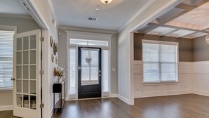 A spacious room with hardwood flooring, a black door, and large windows with blinds. - Spacious 5BR Masters Retreat: Heated Pool/Spa, Theater, Basketball Court & More! (Evans)