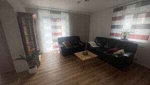 Ett vardagsrum med två svarta lädersoffor, ett soffbord i trä och en krukväxt.