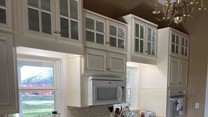 Una cocina con armarios blancos, estufa de acero inoxidable, microondas y refrigerador.