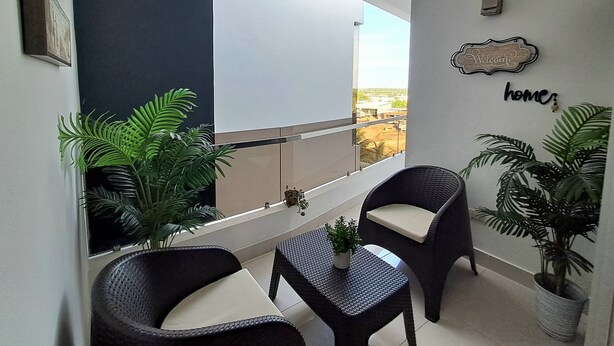 Un balcon avec deux fauteuils en osier, une petite table et des plantes en pot.