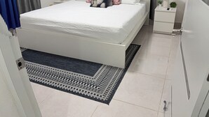 Une chambre à coucher moderne, avec un lit, des rideaux, une table de chevet, une lampe et un climatiseur fixé au mur.