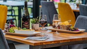 A restaurant setting with a bottle of wine, two glasses of wine, a plate of food, and a basket of fries.