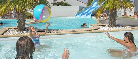 Un espace piscine doté d’un toboggan et bordé de palmiers.