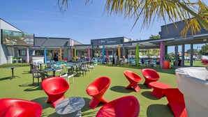 Un espace extérieur aménagé avec des tables et des chaises, un bar et un restaurant appelé « La Table Gabelous ».