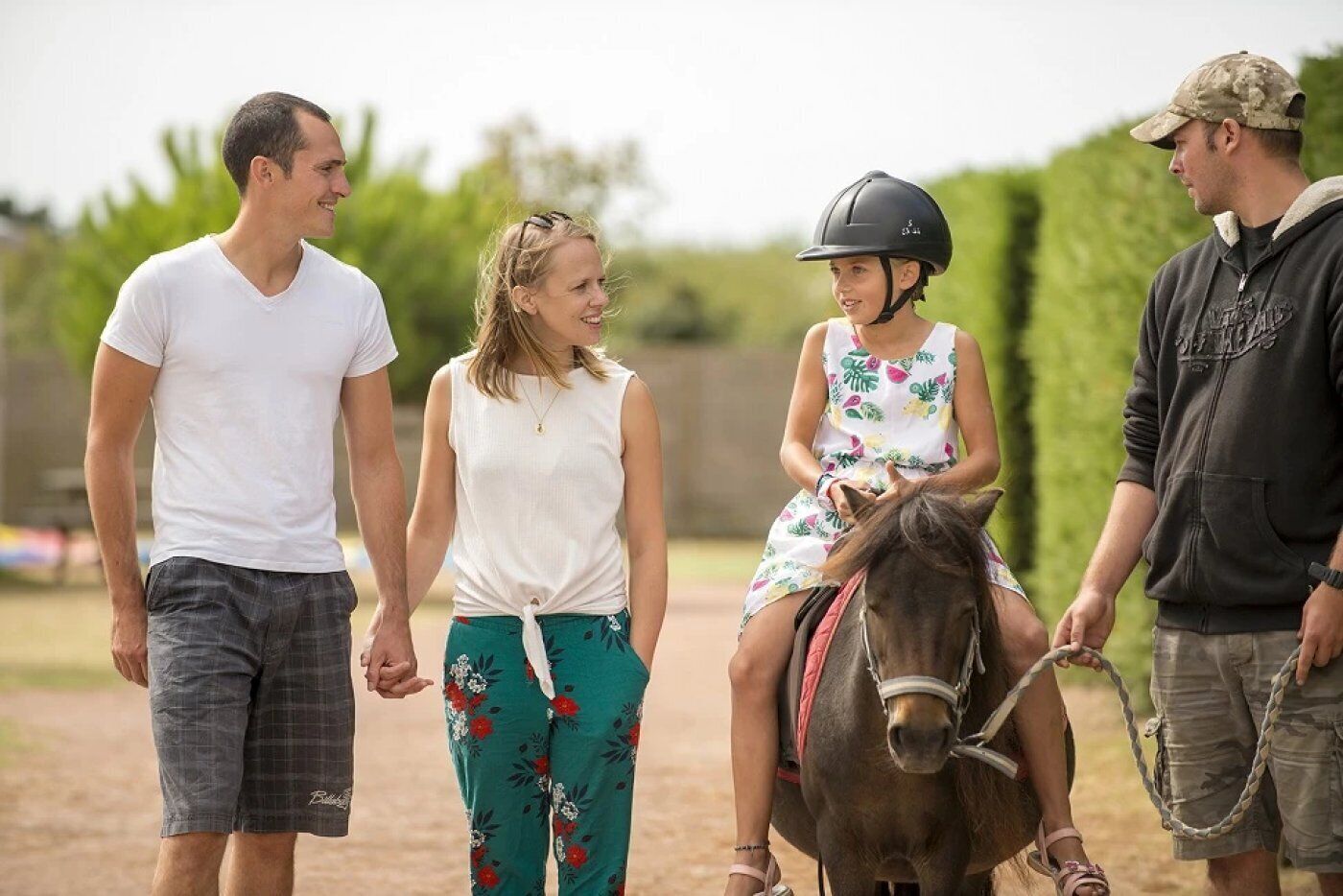 A group of people, including a child on a pony, standing on a dirt path.