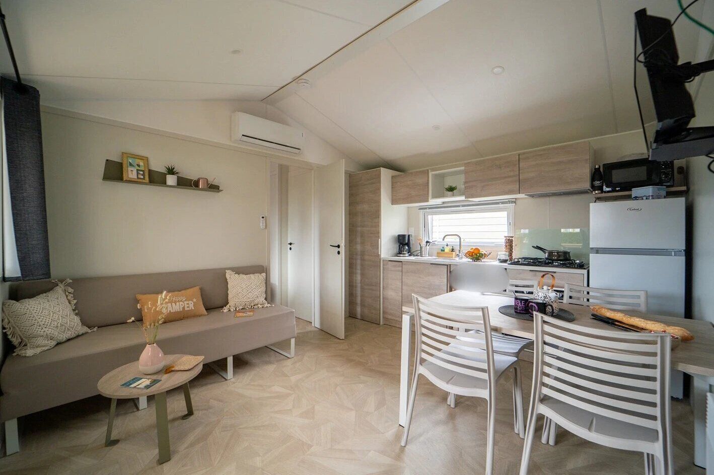 A compact living space with a sofa, dining table, chairs, kitchenette, and a TV.