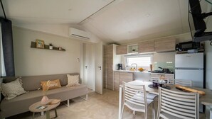 Un espace de vie compact comprenant un canapé, une table à manger, des chaises, un coin cuisine et un téléviseur.