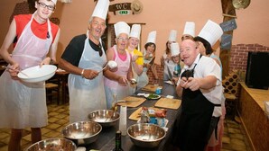 Un grupo de personas con gorros de chef y delantales reunidas alrededor de una mesa con utensilios de cocina e ingredientes.