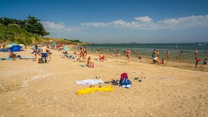 A beach with people sunbathing and swimming, umbrellas, and a yellow kayak on the sand.