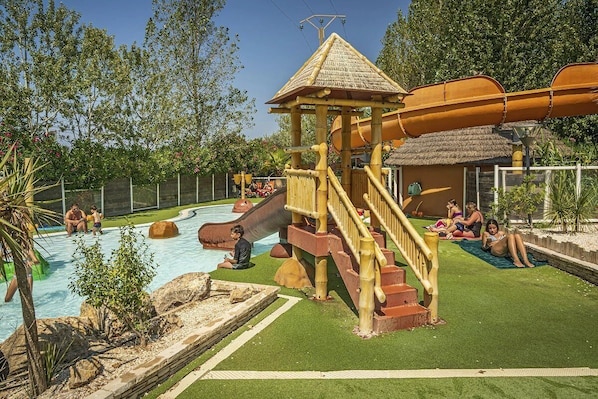 A playground with a slide, a small hut, and a pool area.
