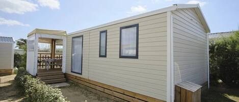 A single-story mobile home with a covered porch and a small deck.
