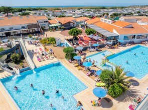 A resort with two large swimming pools, a water slide, and a covered seating area with umbrellas.