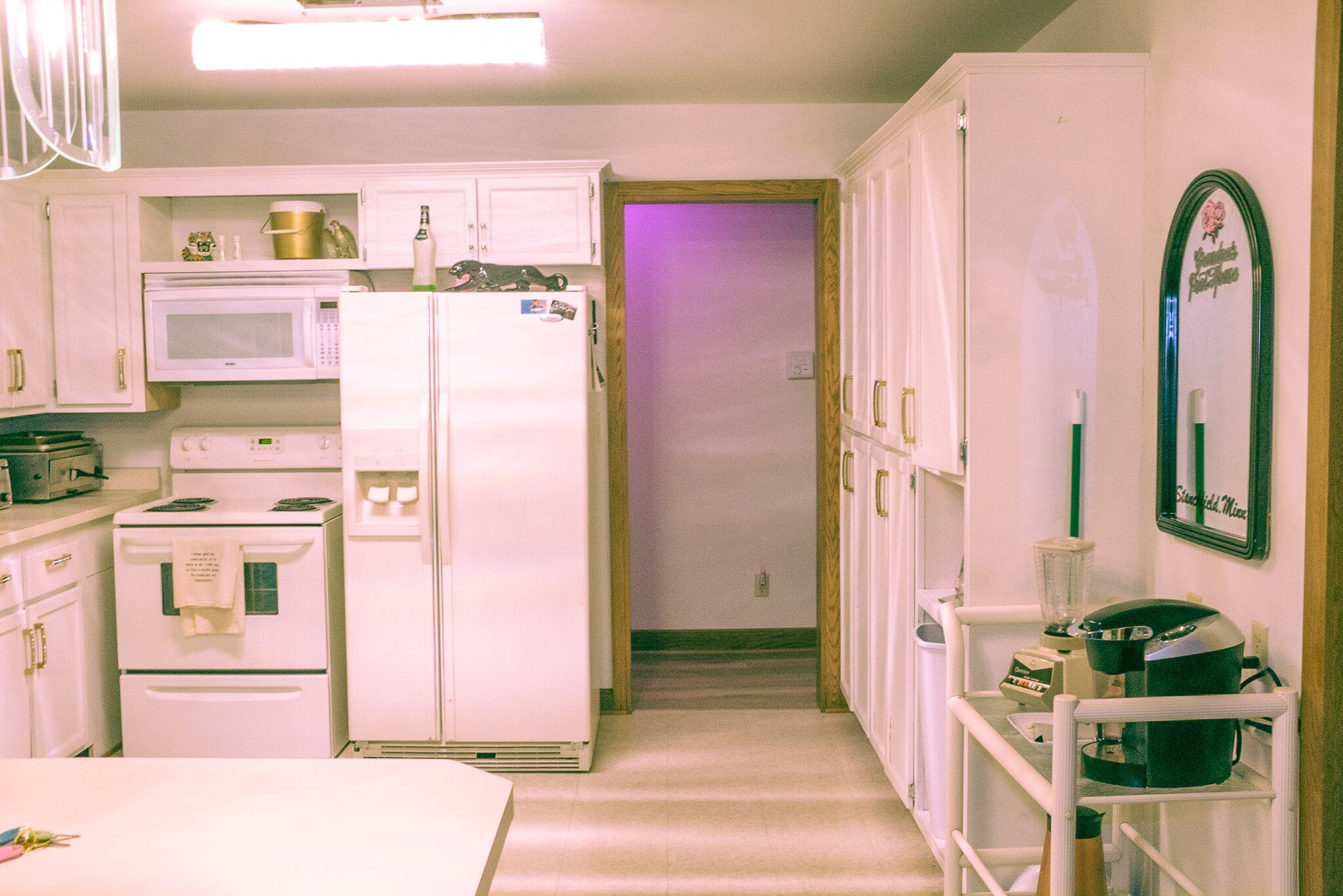 A compact kitchen with white appliances, a coffee maker, and a refrigerator.