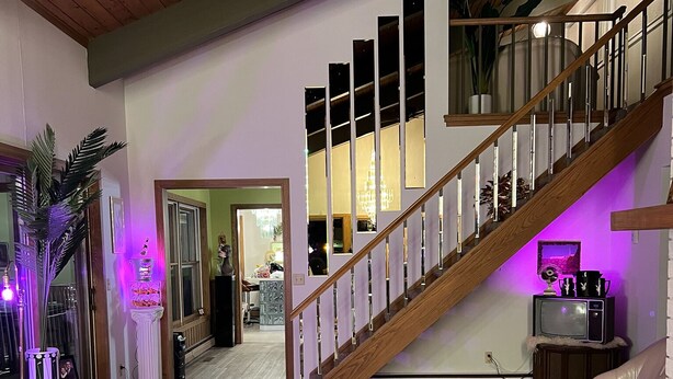 Un salon spacieux avec un escalier en bois, une table basse ronde de couleur beige et un canapé en cuir.