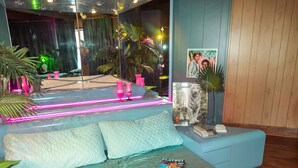 Une chambre moderne avec un lit en verre, une literie de couleur turquoise et un magazine Playboy sur le lit.