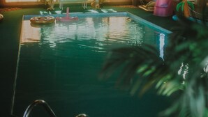 Une piscine intérieure à l’eau claire, avec un échelle et quelques chaises longues.