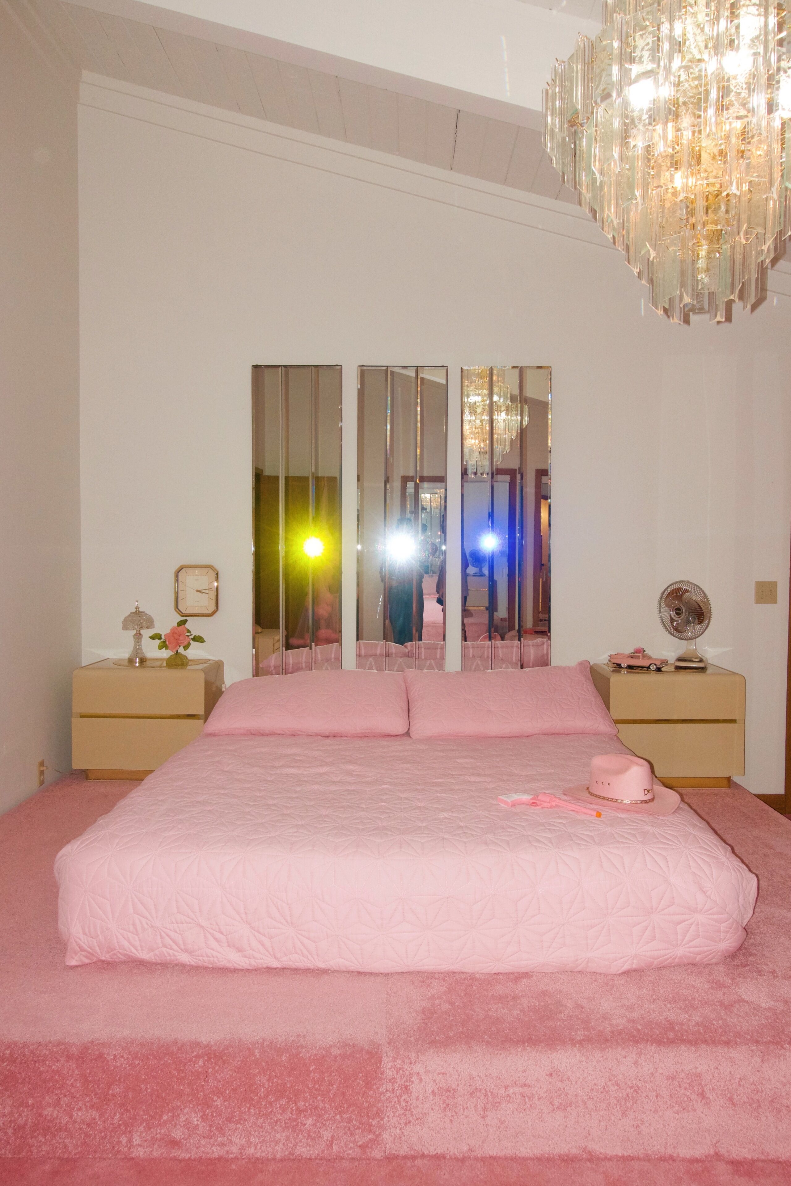 Une chambre à coucher avec un grand lit, un lustre et un miroir.