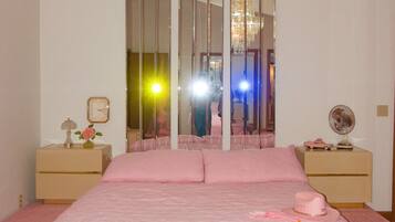 Une chambre à coucher avec un grand lit, un lustre et un miroir.