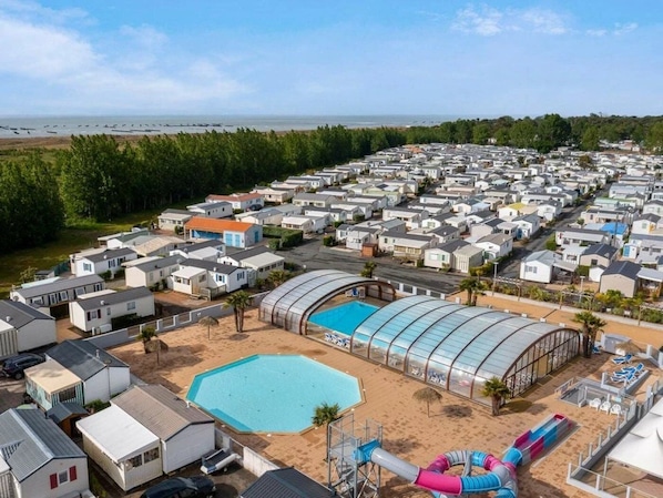 A caravan park with multiple mobile homes, a swimming pool, and a water slide.