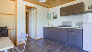 Cocina compacta con armarios de madera, microondas, estufa y cafetera.