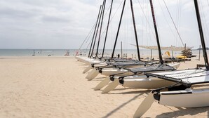 A beach with multiple sailboats lined up on the sand, a clear sky, and the ocean in the background. - Hôtel Miléade Les Pléïades  La Baule (La Baule-Escoublac)