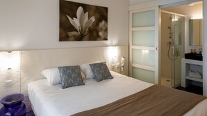 A hotel room with a bed, a bedside table, a nightstand, a bathroom with a shower, and a mirror. - Hôtel Miléade Les Pléïades  La Baule (La Baule-Escoublac)