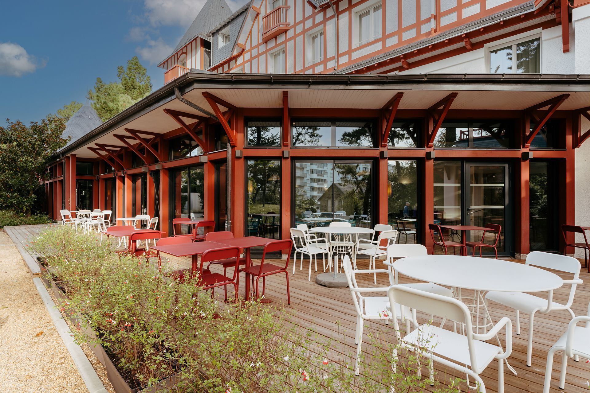 An outdoor seating area with tables and chairs, large windows, and a wooden deck.