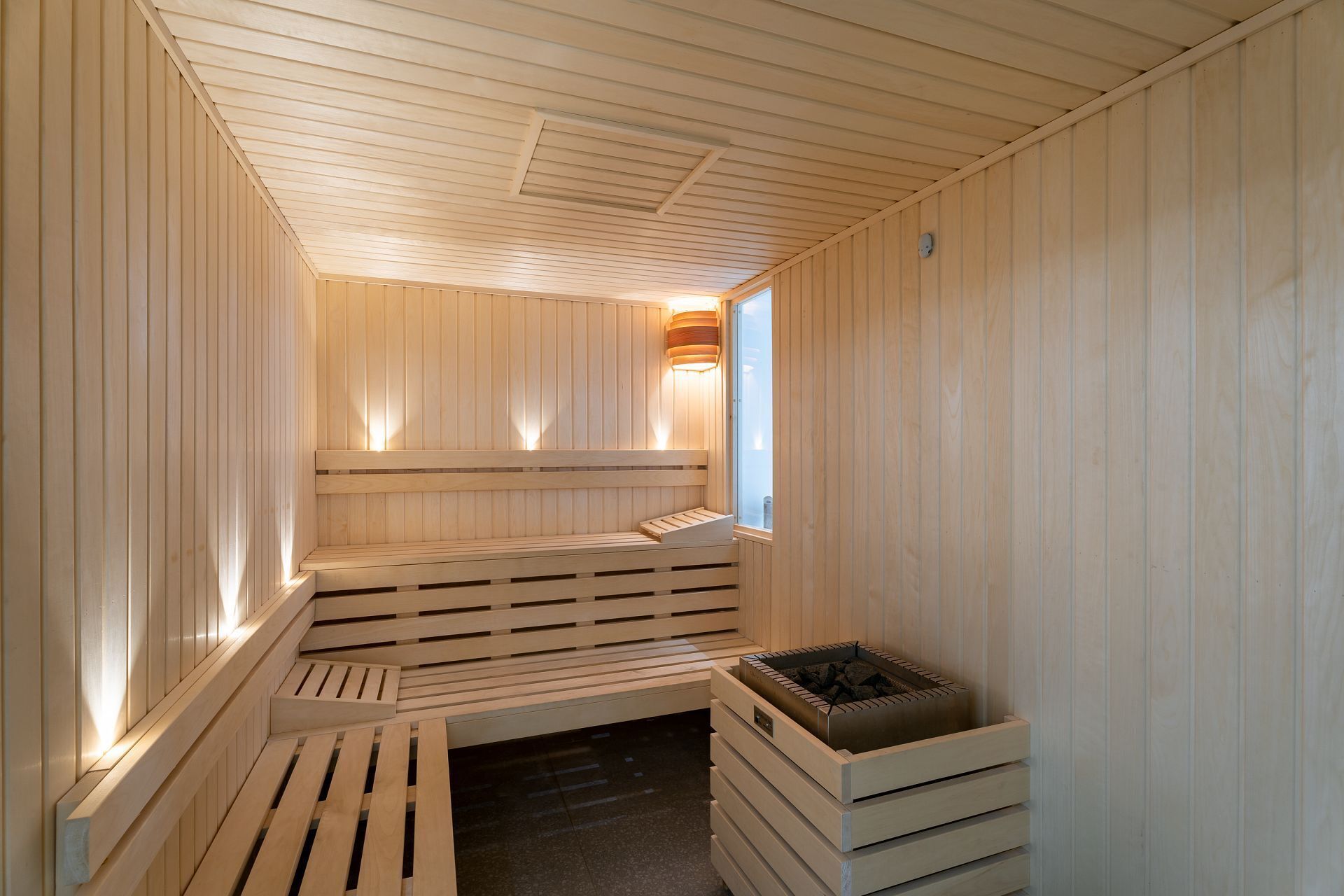 A sauna with wooden benches and a central heating element.