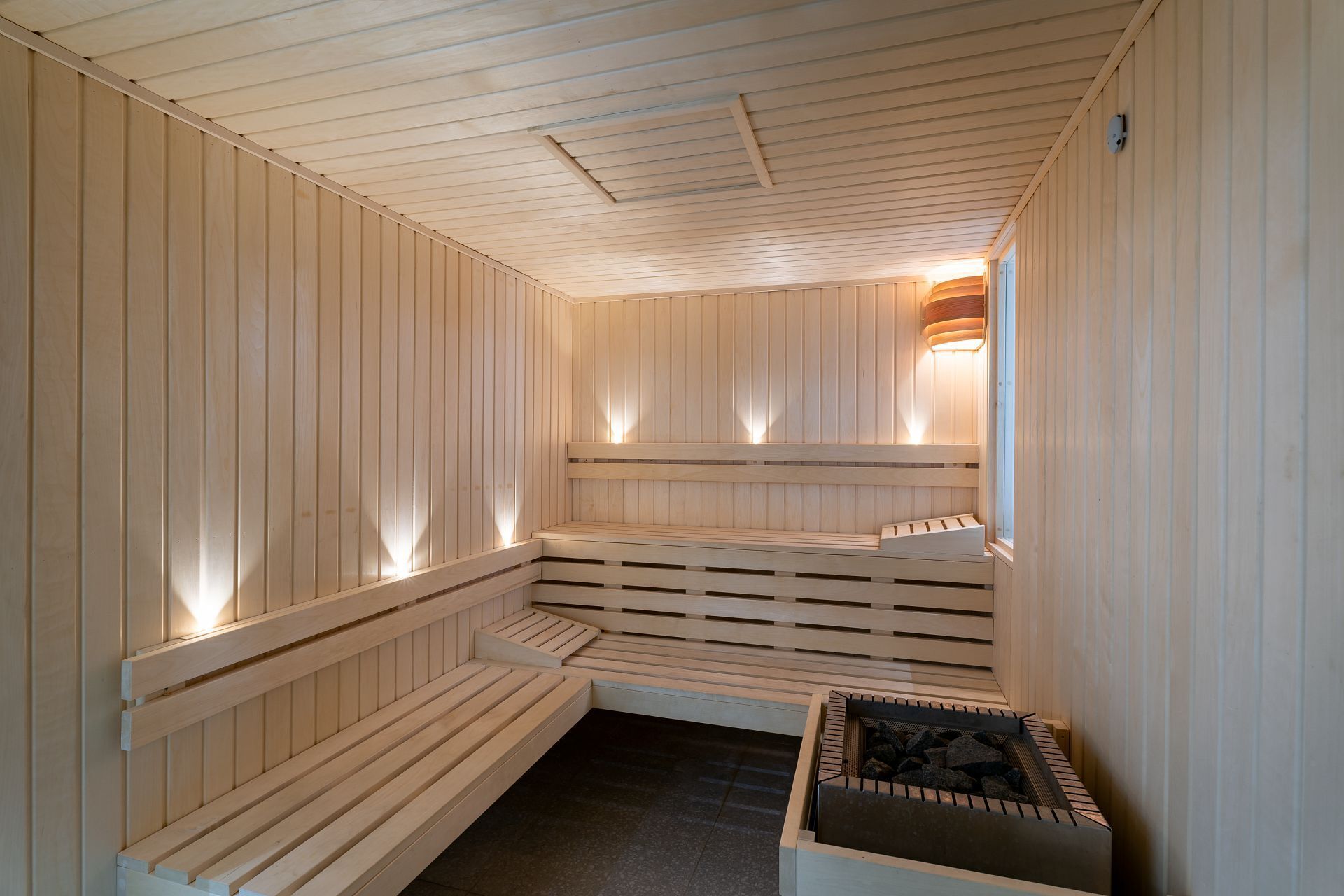 Een sauna met houten banken en een stenen wasbak.