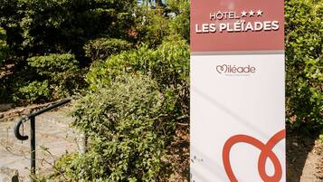A sign for Hotel Les Pleiades with a logo and name.