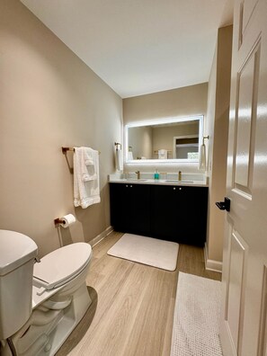 Une salle de bain comprenant des toilettes, un lavabo, un miroir et un porte-serviettes.