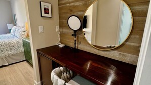 A room with a wooden wall, a round mirror, a desk, and a chair.