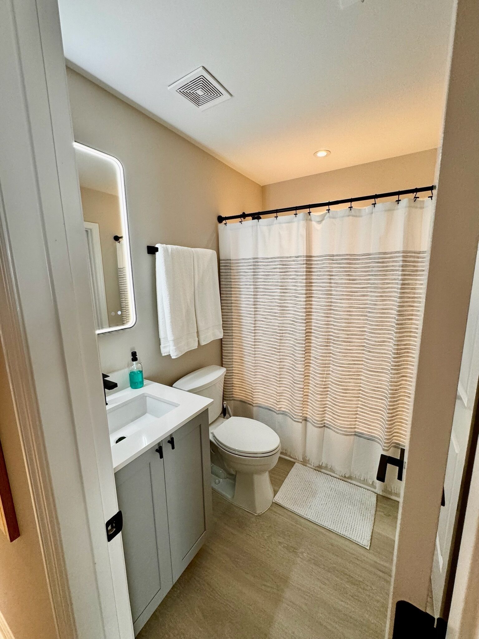 Un baño moderno con lavamanos, espejo y retrete blancos.