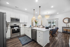 A modern kitchen with white cabinetry, stainless steel appliances, and a central island.