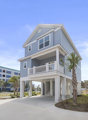 A two-story house with a balcony, a covered entryway, and a palm tree in the front yard.