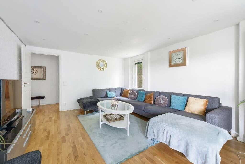 A modern living room with a grey sofa, a white coffee table, and a blue rug.