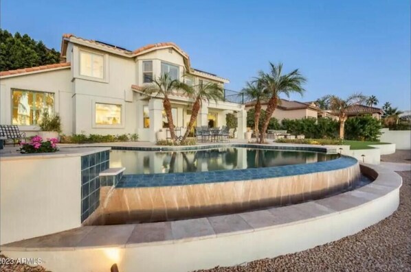 A two-story house with a swimming pool, palm trees, and a well-maintained garden. - Lakefront Getaway with Infinity Pool and Pontoon (Glendale)