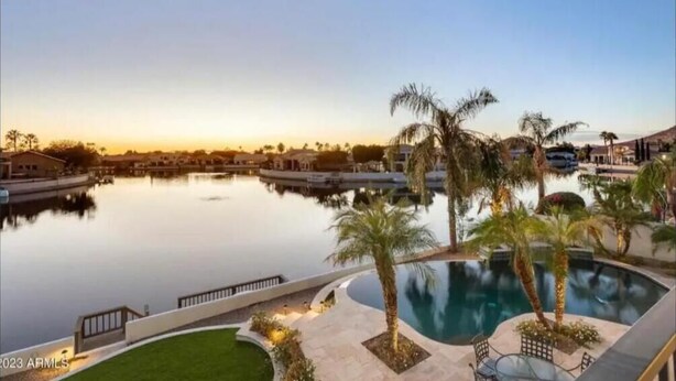 Un resort con una gran piscina, palmeras y vistas al atardecer.