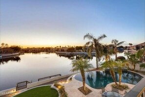 Ein Resort mit großem Pool, Palmen und Blick auf den Sonnenuntergang.