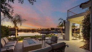 Un patio al aire libre con mobiliario, piscina y vistas al atardecer.