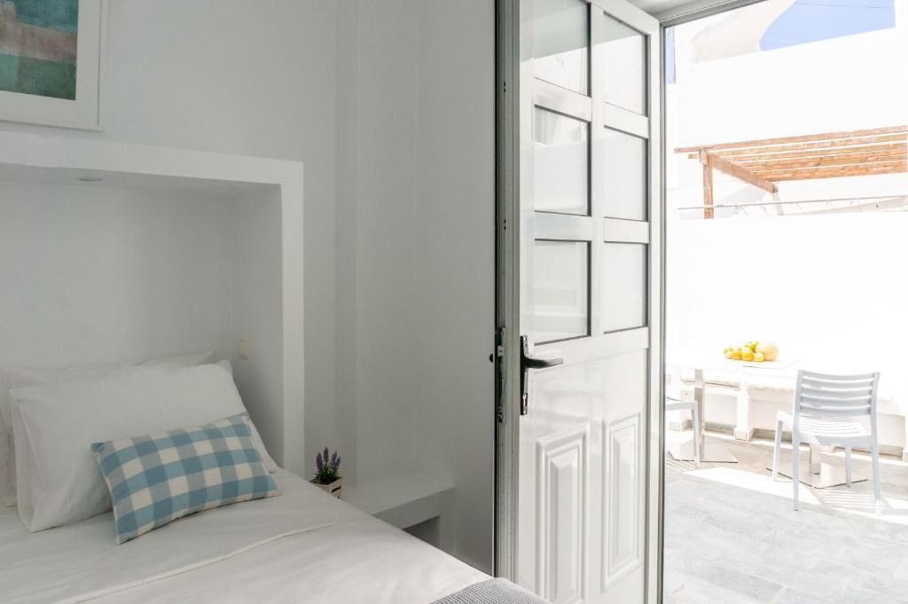 A bedroom with a bed, a checkered pillow, and a view of an outdoor patio with a table and chairs.