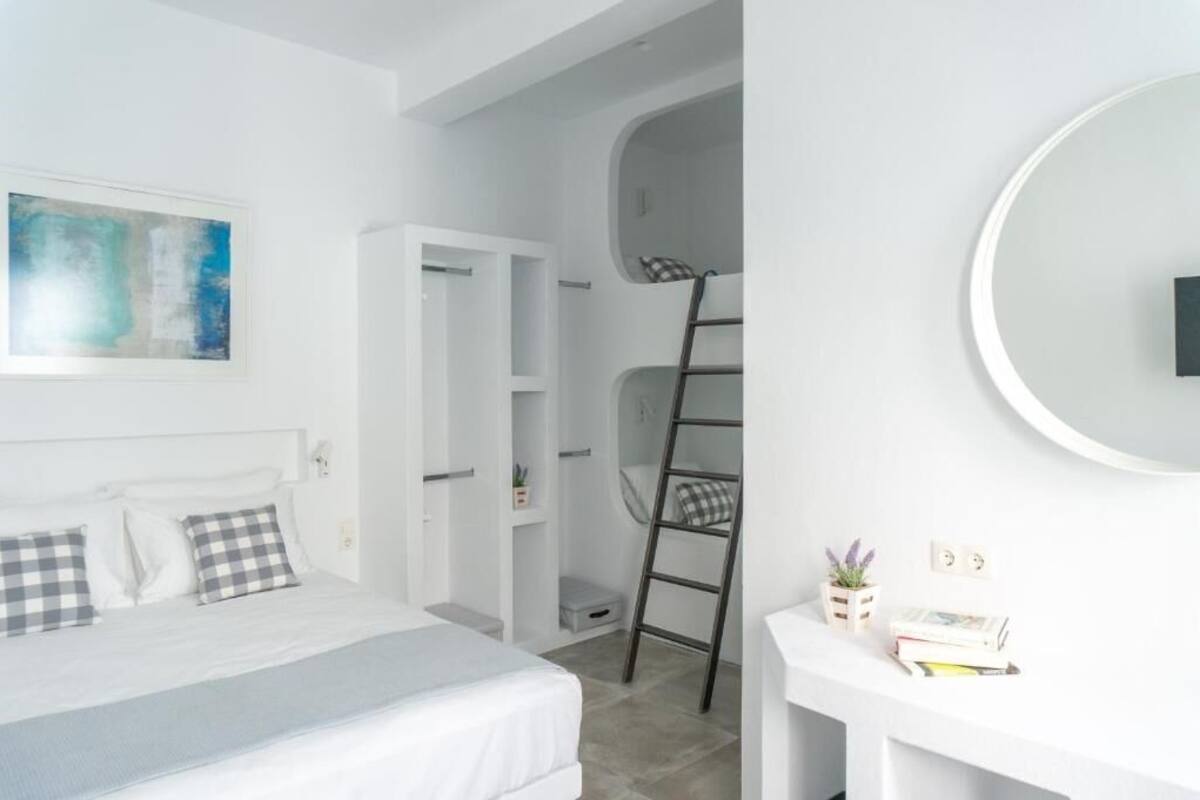 A modern bedroom with a bed, a wardrobe, a ladder, and a desk with books.