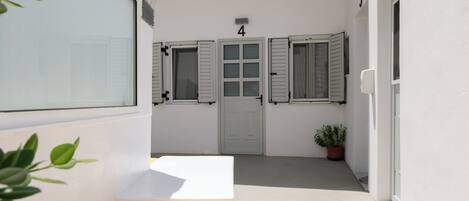 A narrow corridor with a bench, a door marked with the number 4, and a potted plant.