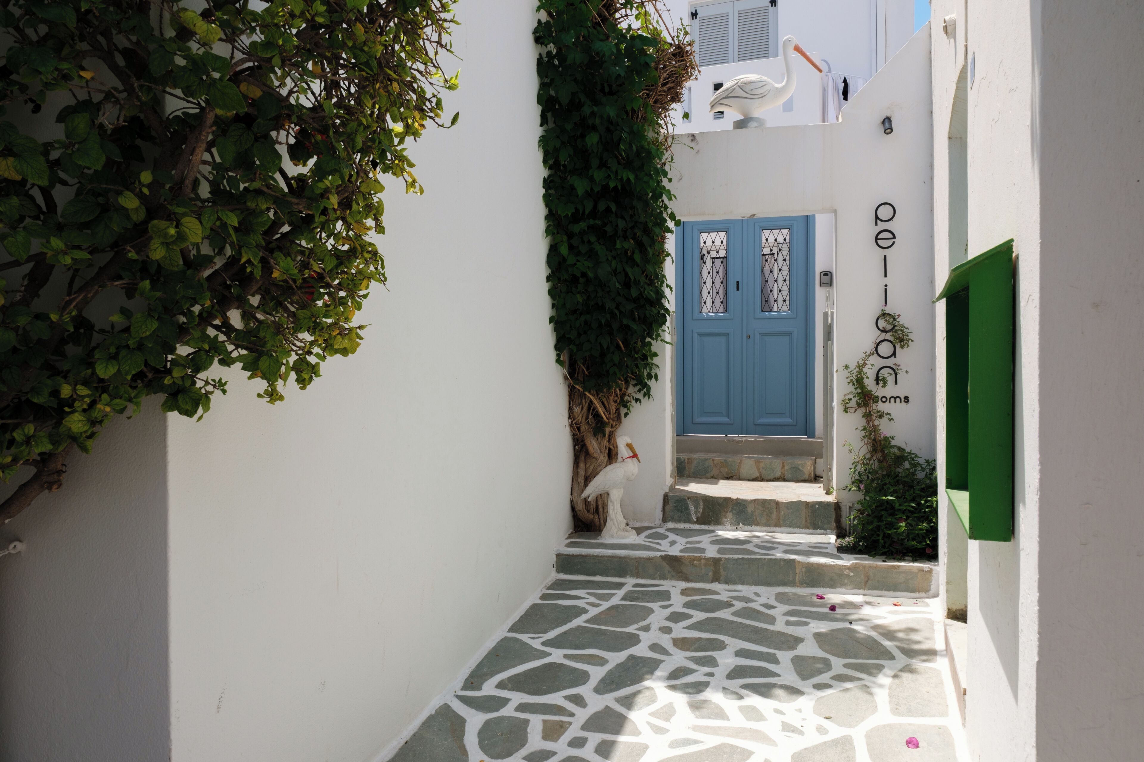 A narrow alleyway with a blue door, stone steps, and greenery.