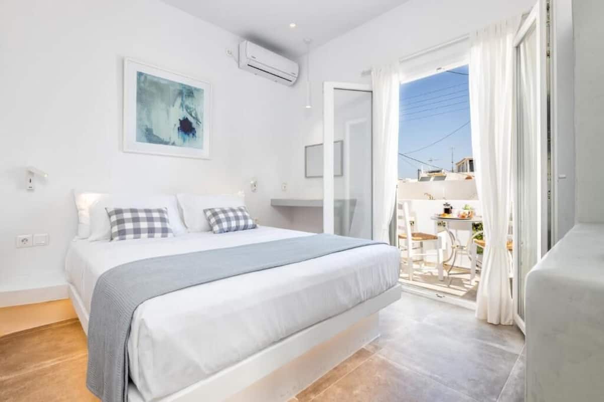 A bedroom with a bed, a window, and a balcony.