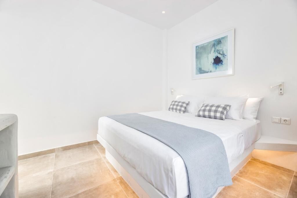 A bedroom with a bed, a wall-mounted artwork, and a light switch.