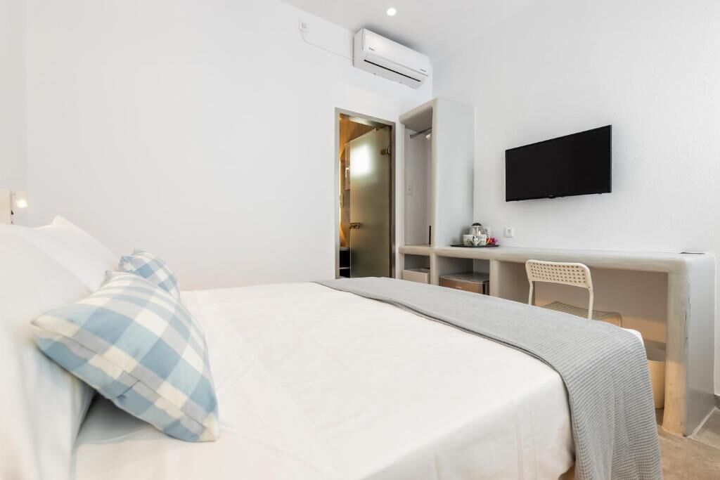 Une chambre d’hôtel équipée d’un lit, d’un bureau, d’une chaise et d’un téléviseur à écran plat fixé au mur.