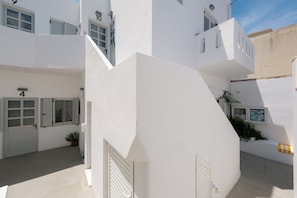 A white building with a door marked '4' and a window with shutters. - Pelican Paros  (Paros)
